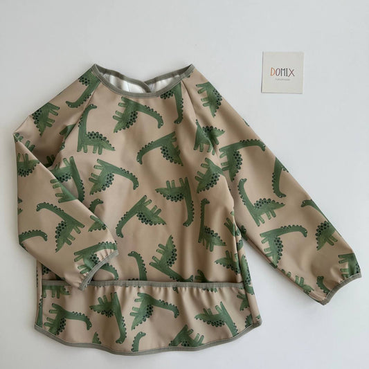 Children's shirt with green dinosaur pattern on a beige background