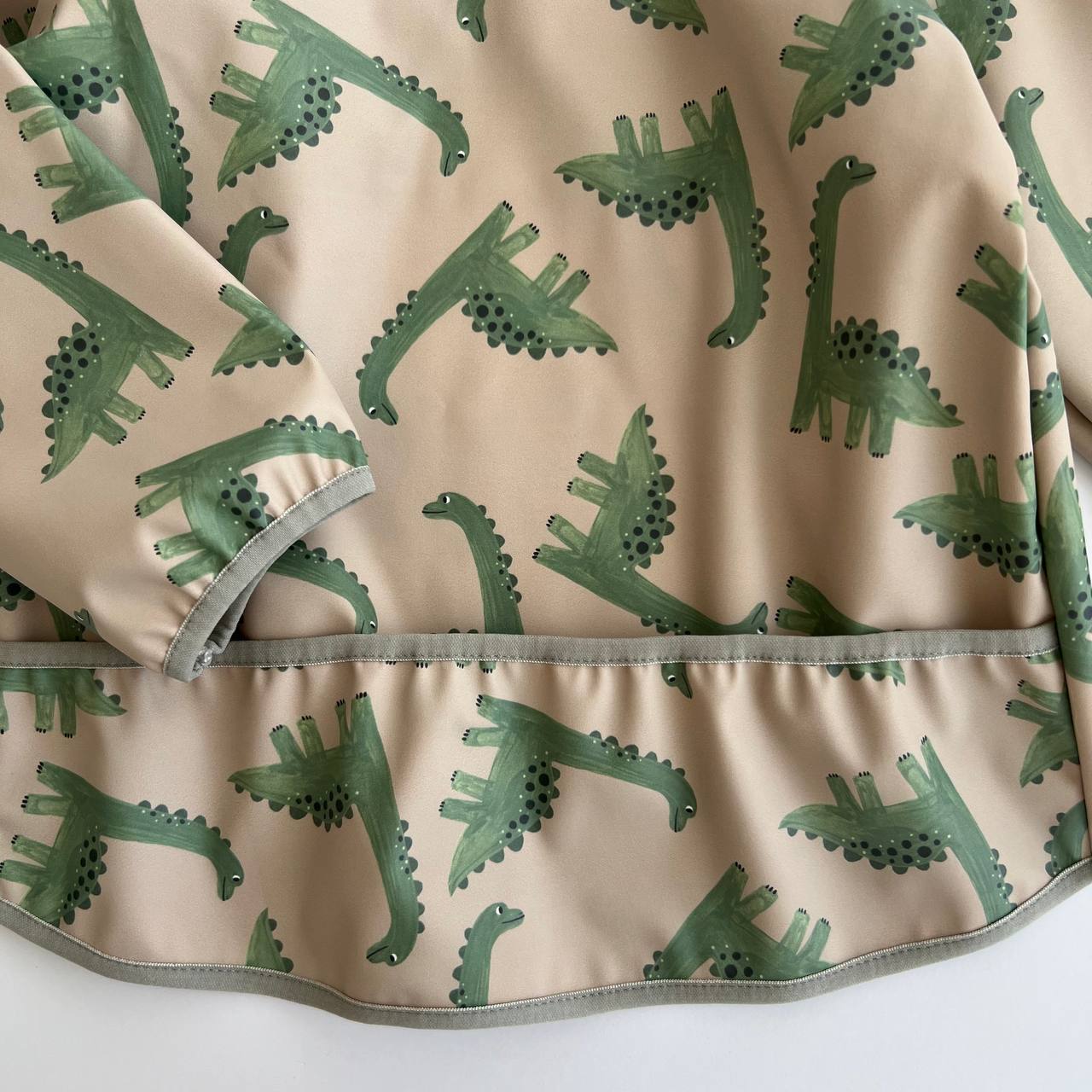 Fabric with green dinosaur pattern on a beige background