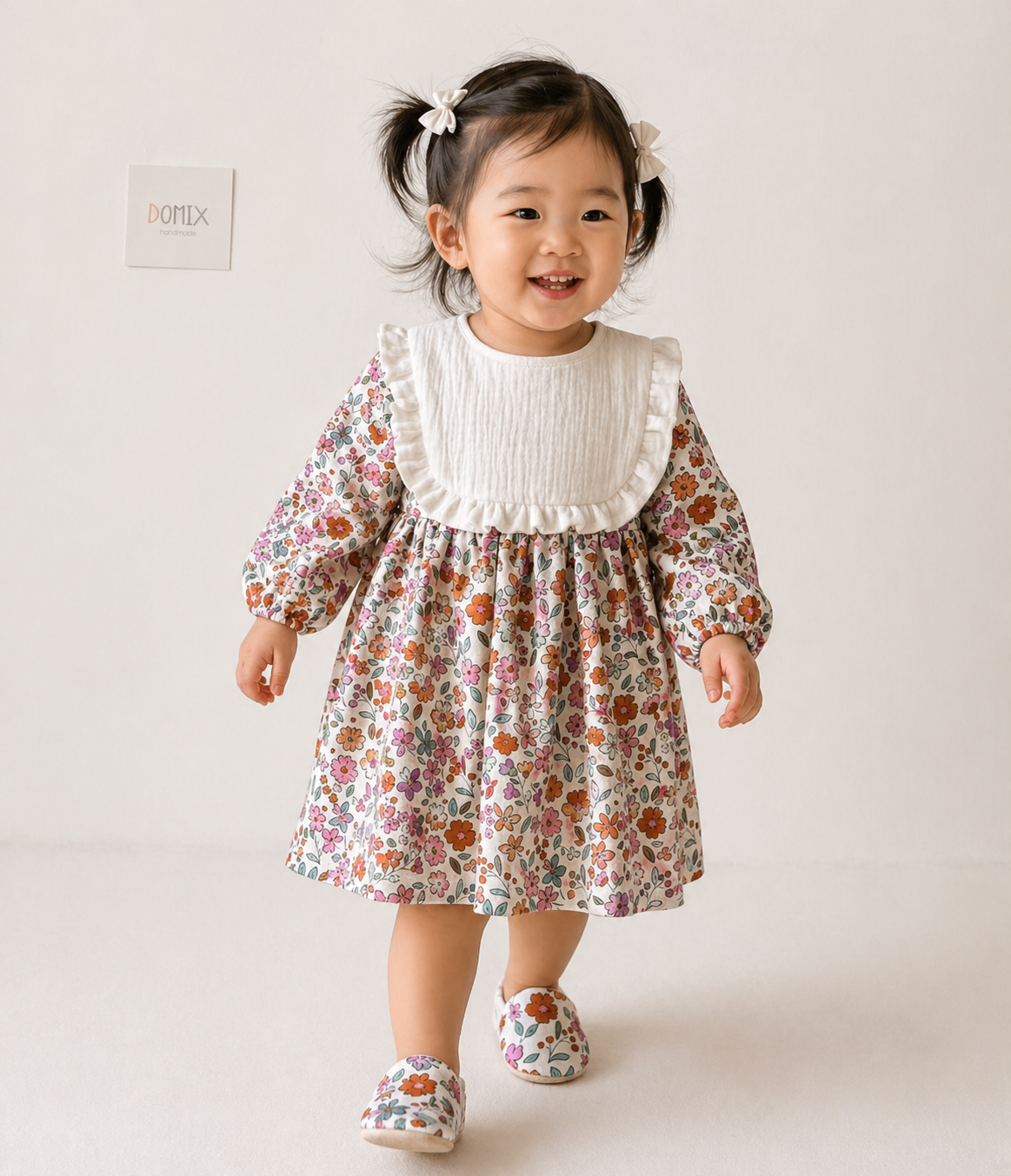 Child wearing a floral dress with a white collar against a plain background